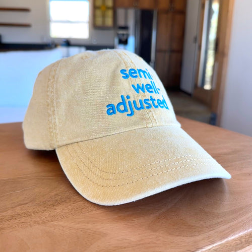 Yellow cap with 'semi well adjusted' text on a wooden surface in a kitchen setting